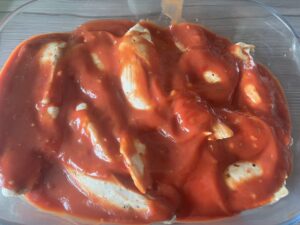 Covering chicken with sauce - Pizza Chicken